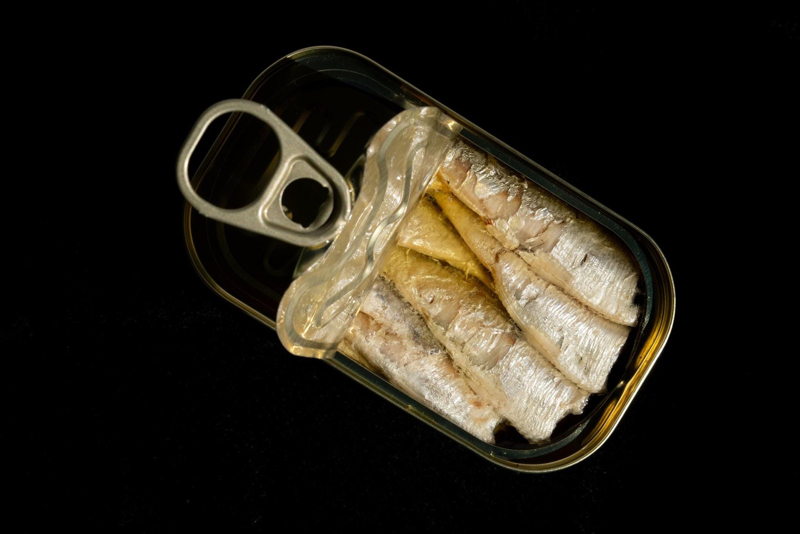 Geöffnete Vintage Fischkonserve in Öl auf schwarzem Hintergrund